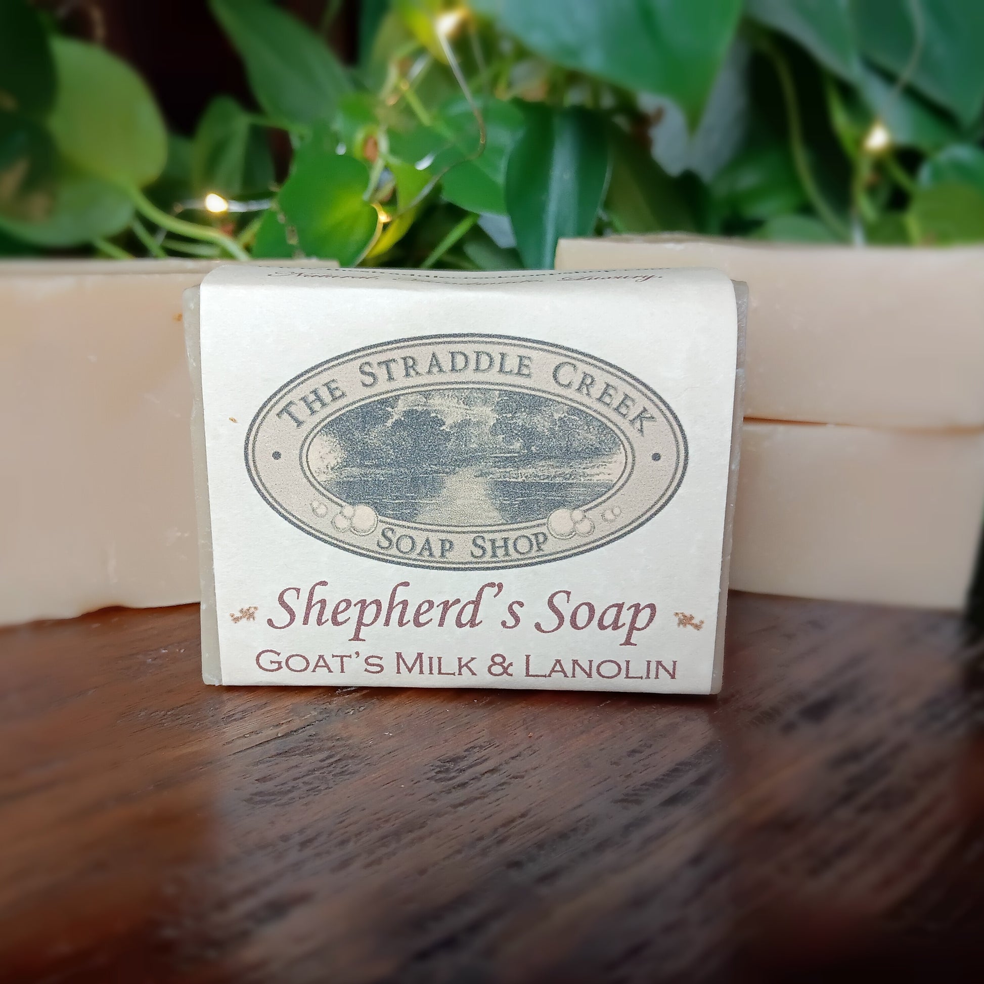 Shepherd's Soap bar from The Straddle Creek Soap Shop on a wooden surface with greenery in the background.