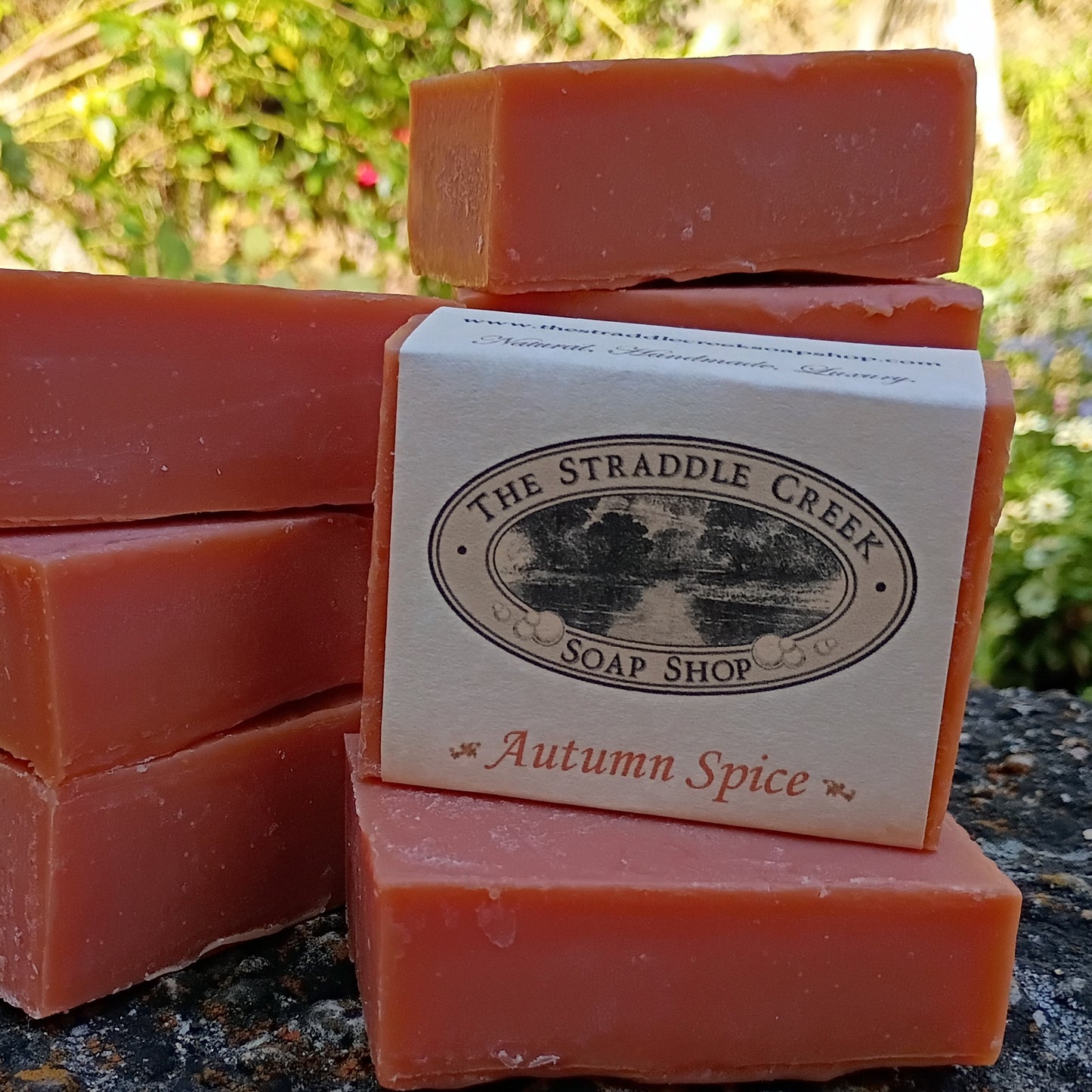 Bars of soap with a 'The Straddle Creek Soap Shop' box labeled 'Autumn Spice' on a natural background.